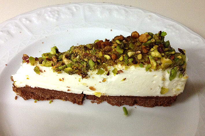 Cheesecake alla vaniglia con base di biscotto al cioccolato e ricoperta di pistacchio